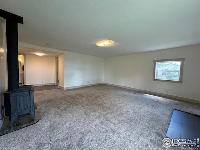 unfurnished living room featuring carpet floors and a wood stove