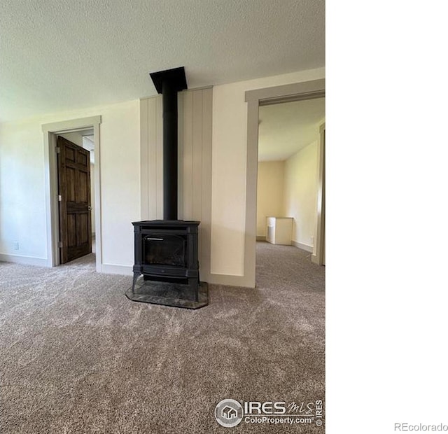 unfurnished living room with carpet floors, a textured ceiling, and a wood stove