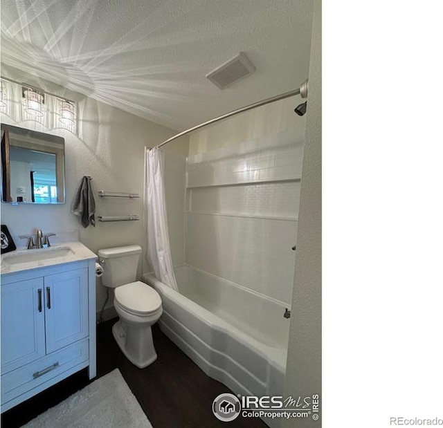 full bathroom featuring vanity, a textured ceiling, wood-type flooring, shower / tub combo with curtain, and toilet