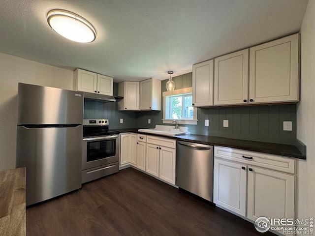 kitchen with pendant lighting, dark hardwood / wood-style floors, sink, white cabinetry, and appliances with stainless steel finishes