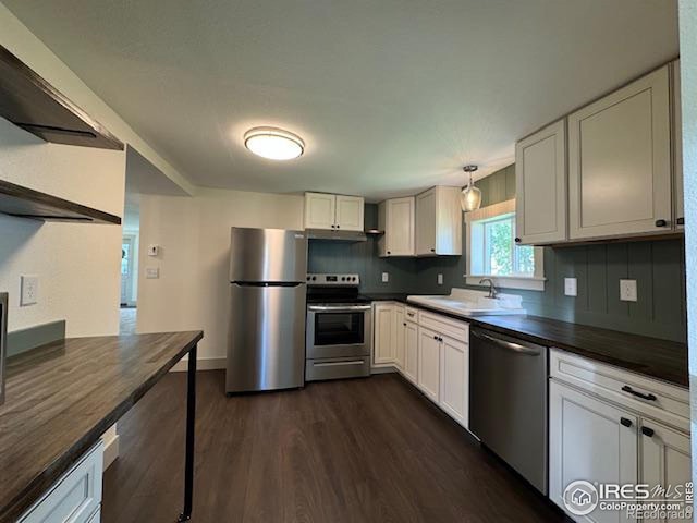 kitchen with dark wood-type flooring, sink, white cabinets, decorative backsplash, and appliances with stainless steel finishes