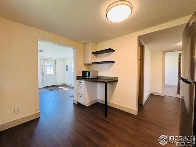 kitchen with appliances with stainless steel finishes, dark hardwood / wood-style flooring, and white cabinets