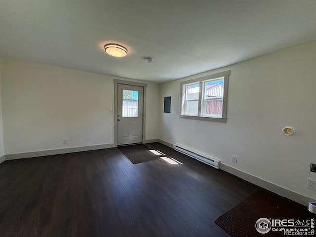 empty room with a baseboard heating unit and dark hardwood / wood-style floors