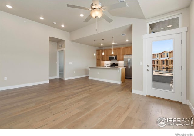 kitchen with ceiling fan, stainless steel appliances, light hardwood / wood-style flooring, and lofted ceiling