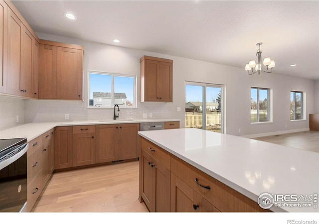 kitchen with plenty of natural light, light hardwood / wood-style floors, sink, and backsplash