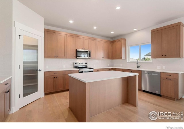 3288 Buffalo Grass Ln, Wellington, CO 80549 - kitchen featuring appliances with stainless steel finishes, light wood finished floors, decorative backsplash, a kitchen island, and light countertops