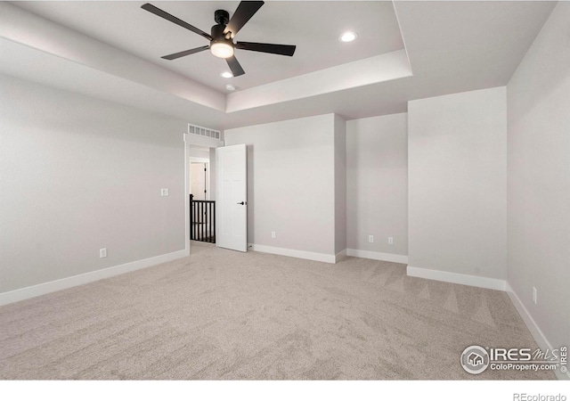 carpeted empty room featuring a tray ceiling and ceiling fan