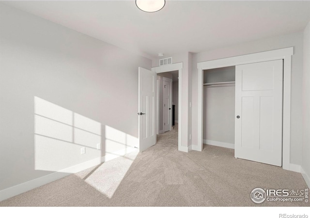 unfurnished bedroom with light colored carpet and a closet