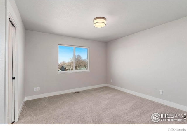 unfurnished room featuring carpet and a textured ceiling