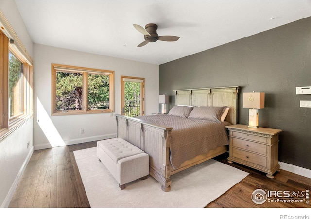 bedroom featuring ceiling fan, multiple windows, and dark hardwood / wood-style floors