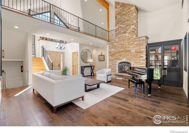 living room featuring a stone fireplace, hardwood / wood-style flooring, and a towering ceiling