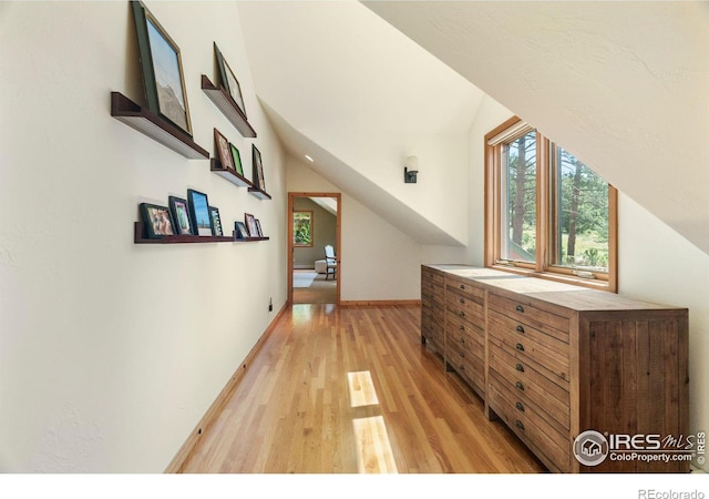 additional living space featuring baseboards, vaulted ceiling, and light wood finished floors