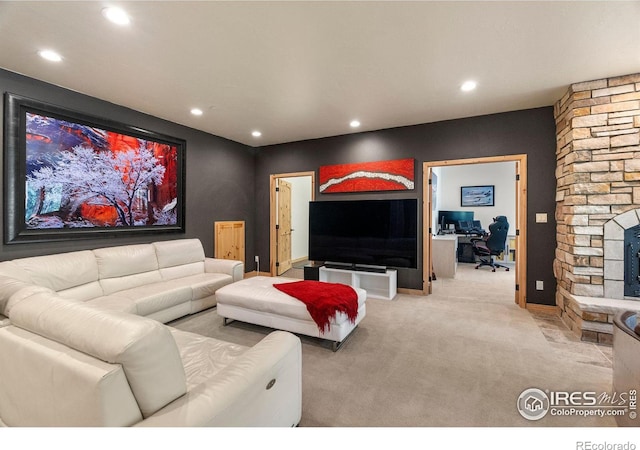 carpeted living room featuring a stone fireplace