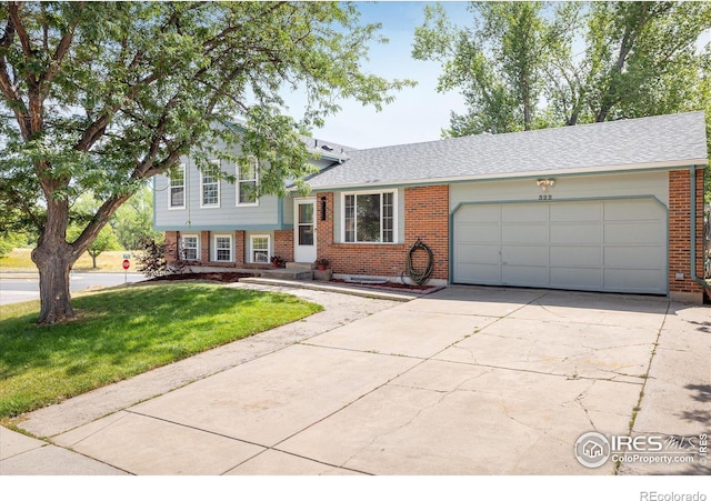 split level home featuring driveway, brick siding, a front lawn, and an attached garage