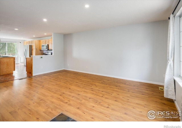 unfurnished living room featuring light wood-type flooring, baseboards, visible vents, and recessed lighting