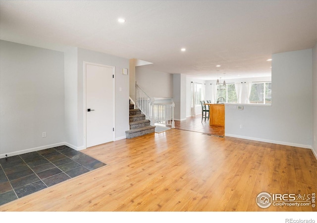 unfurnished room featuring recessed lighting, wood finished floors, baseboards, and stairs