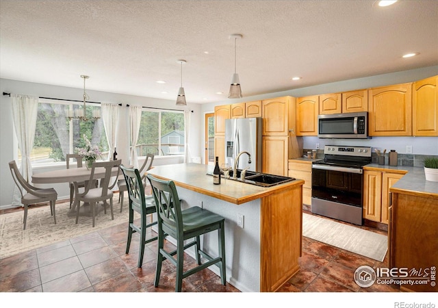 kitchen featuring appliances with stainless steel finishes, a kitchen breakfast bar, a kitchen island with sink, pendant lighting, and a sink