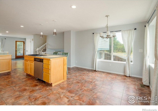 kitchen featuring light brown cabinets, a sink, hanging light fixtures, stainless steel dishwasher, and a center island with sink