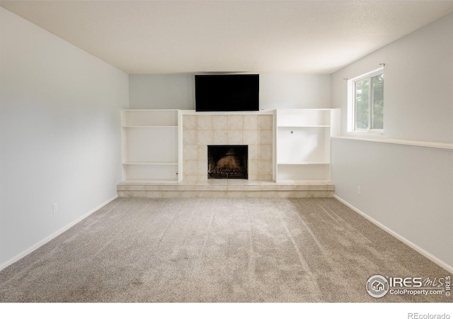 unfurnished living room with carpet flooring, a fireplace, and baseboards