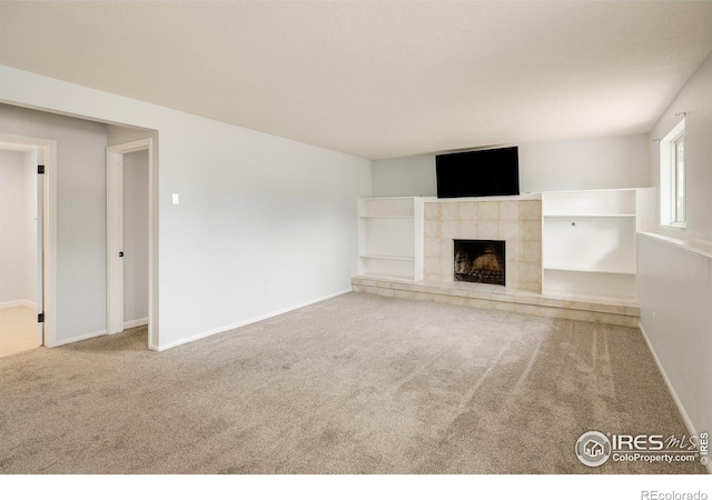 unfurnished living room featuring carpet floors, a fireplace, and baseboards