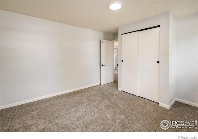 unfurnished bedroom with a closet, carpet, and baseboards