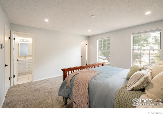 bedroom with a textured ceiling, recessed lighting, connected bathroom, and light colored carpet