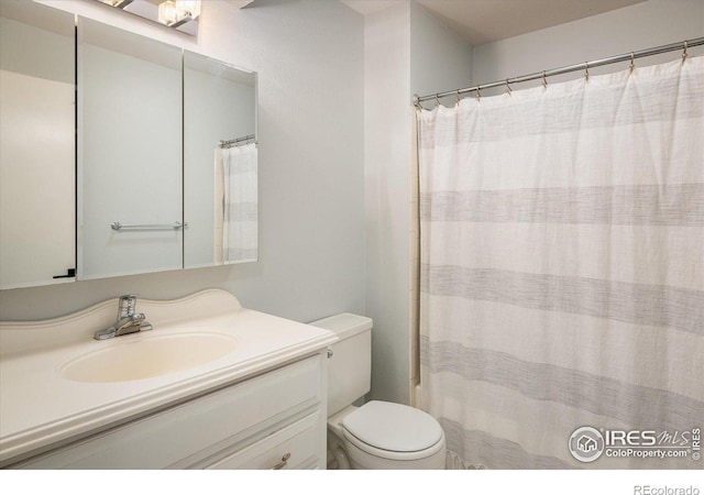 bathroom with toilet, curtained shower, and vanity