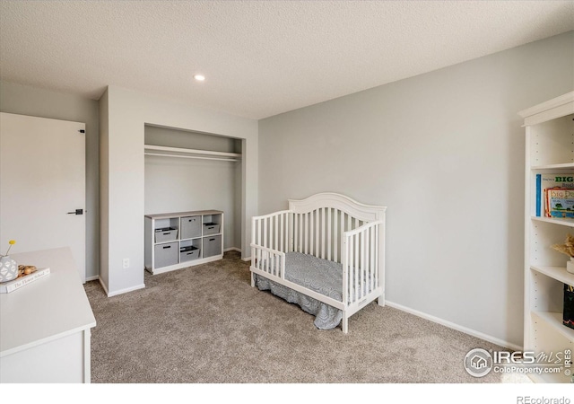 bedroom with a closet, light colored carpet, a textured ceiling, and baseboards