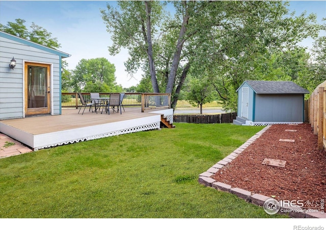 view of yard featuring a storage unit, outdoor dining space, a deck, fence private yard, and an outdoor structure