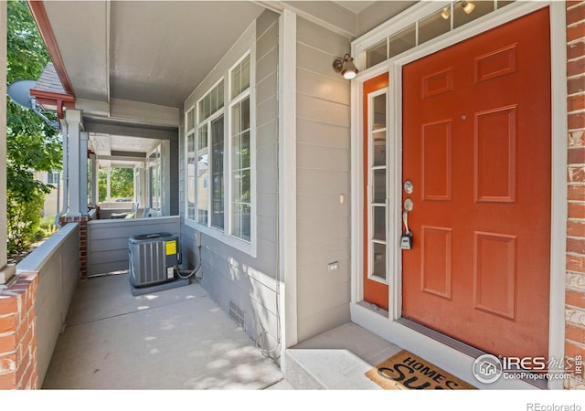 view of exterior entry with a porch and central AC