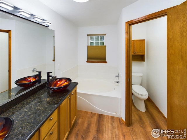 bathroom featuring a bathing tub, hardwood / wood-style flooring, vanity, and toilet