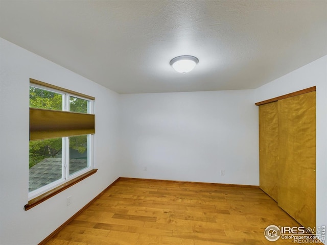 spare room with light wood-type flooring and a textured ceiling