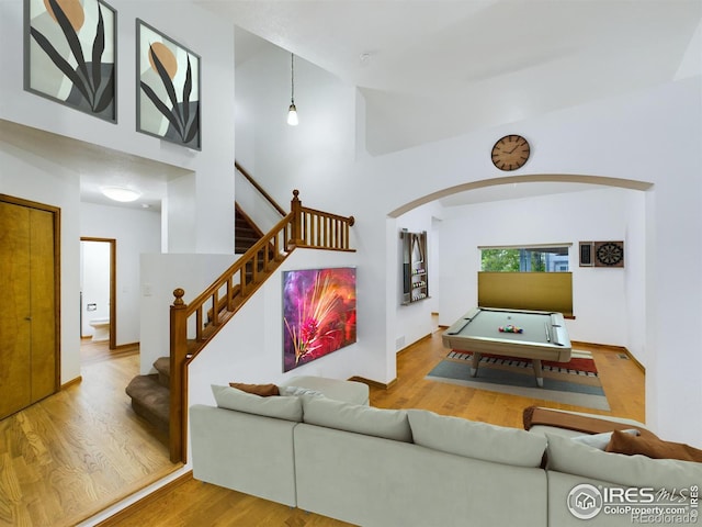 living room with wood-type flooring and a towering ceiling