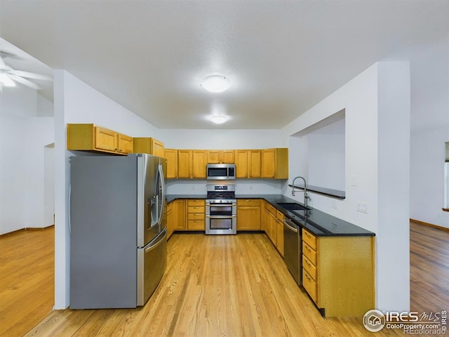 kitchen featuring appliances with stainless steel finishes, light hardwood / wood-style floors, ceiling fan, and sink