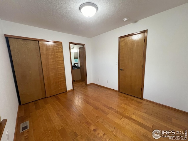 unfurnished bedroom featuring a textured ceiling, light hardwood / wood-style flooring, and a closet