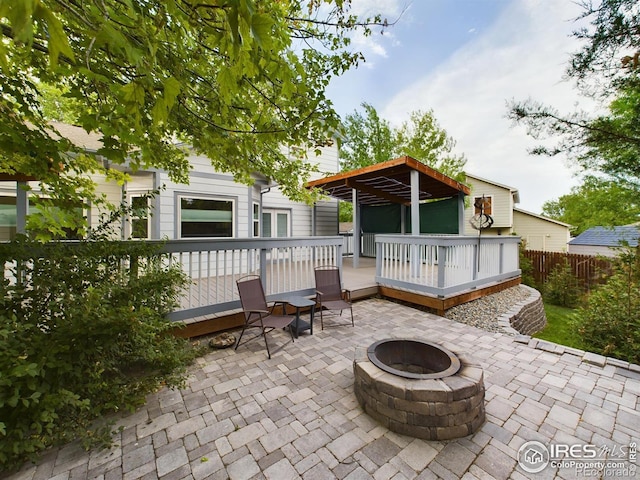 back of property featuring a wooden deck, a patio, and an outdoor fire pit