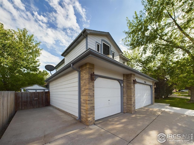 garage with concrete driveway and fence