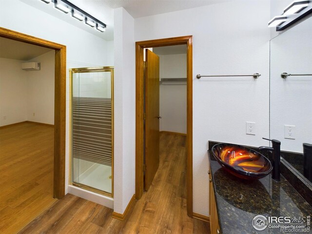 2720 E 121st Pl, Thornton, CO 80241 - full bath featuring vanity, wood finished floors, a wall mounted AC, and a shower stall