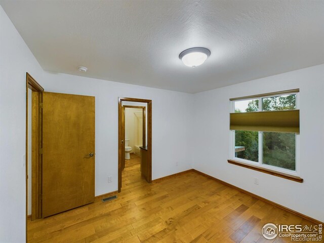 2720 E 121st Pl, Thornton, CO 80241 - unfurnished bedroom with a textured ceiling, light wood-type flooring, baseboards, visible vents, and ensuite bath