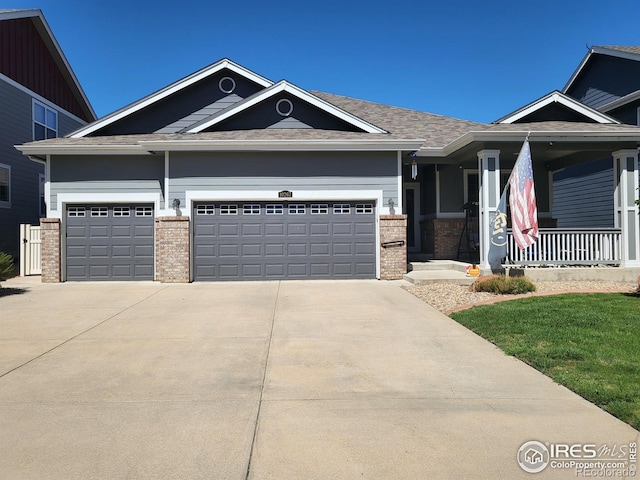 view of front of property with a garage, driveway, brick siding, and covered porch