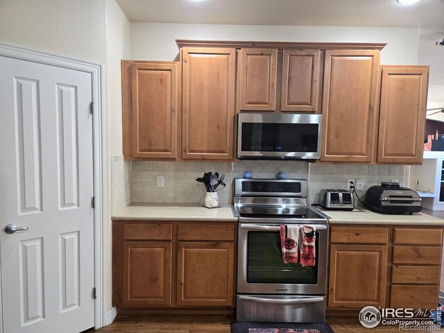 kitchen with light countertops, appliances with stainless steel finishes, backsplash, and brown cabinets