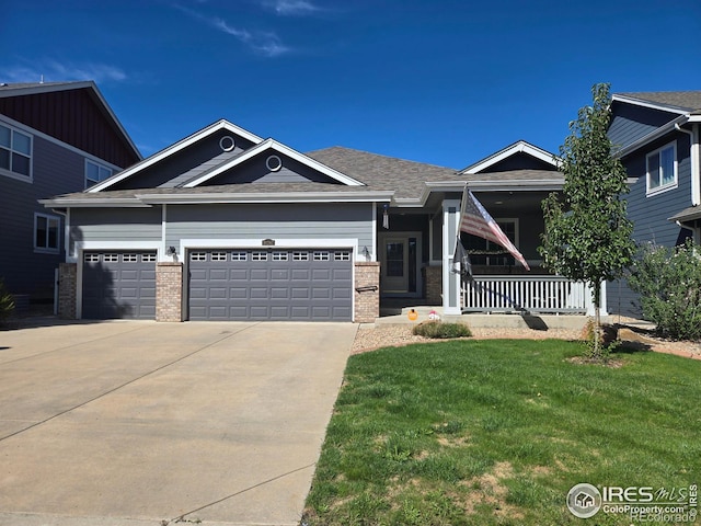 craftsman house with brick siding, a porch, concrete driveway, an attached garage, and a front lawn