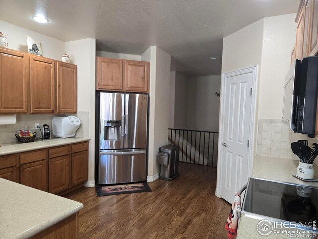 kitchen featuring brown cabinets, dark wood-style floors, light countertops, and stainless steel fridge with ice dispenser