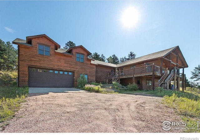 log home with a wooden deck and a garage