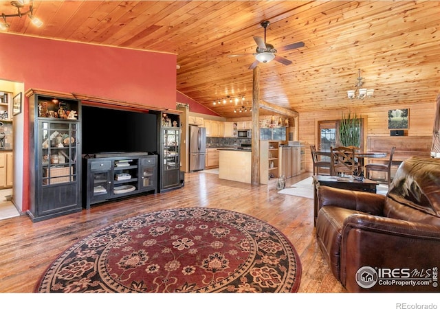 living room with wooden walls, ceiling fan, hardwood / wood-style floors, and high vaulted ceiling