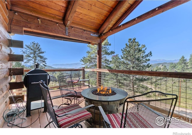 wooden terrace featuring a mountain view and an outdoor fire pit