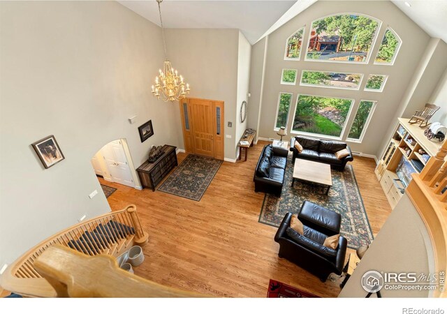 living room featuring high vaulted ceiling, an inviting chandelier, and light wood-type flooring