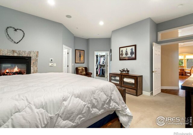 carpeted bedroom featuring a closet, a spacious closet, and a high end fireplace