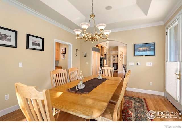 dining room featuring hardwood / wood-style floors, a tray ceiling, a healthy amount of sunlight, and a chandelier