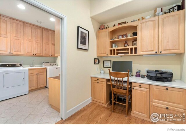 interior space with washer / clothes dryer, built in desk, light wood-type flooring, and light brown cabinetry